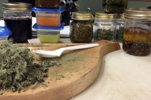 A number of mason jars surround a cutting board processing plants for medicine.