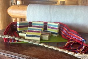 A number of colourful soap bars are neatly stacked with braided sweetgrass.
